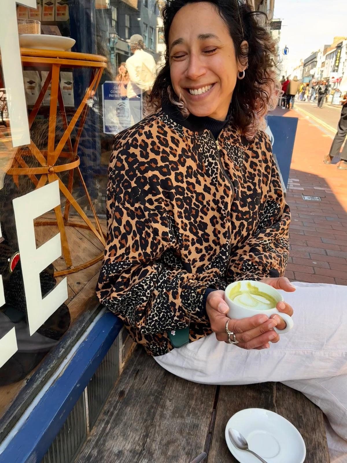 Miran in a leopard-print shirt smiling at a café table