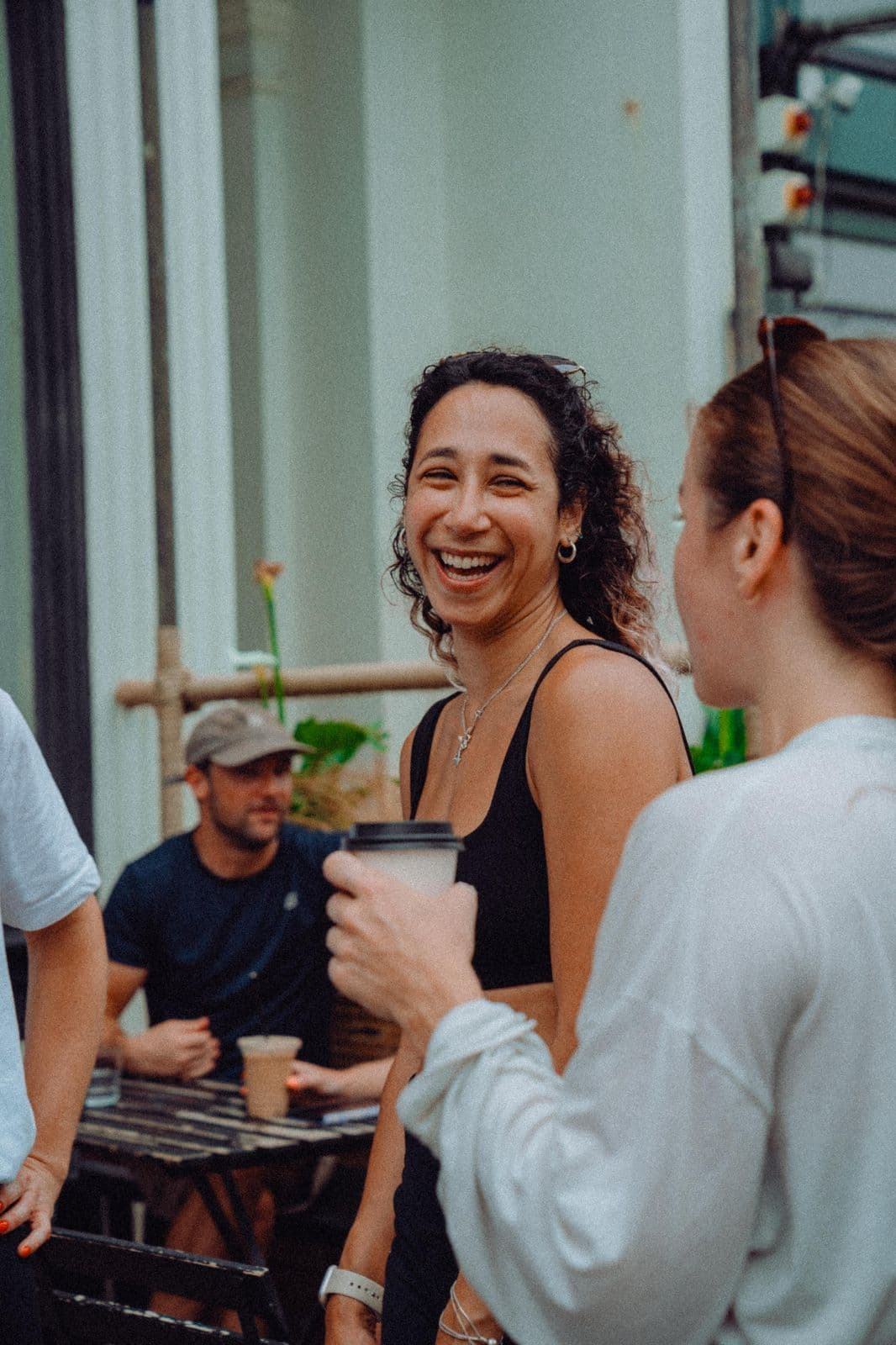 Miran laughing with a coffee in hand on a sunny street