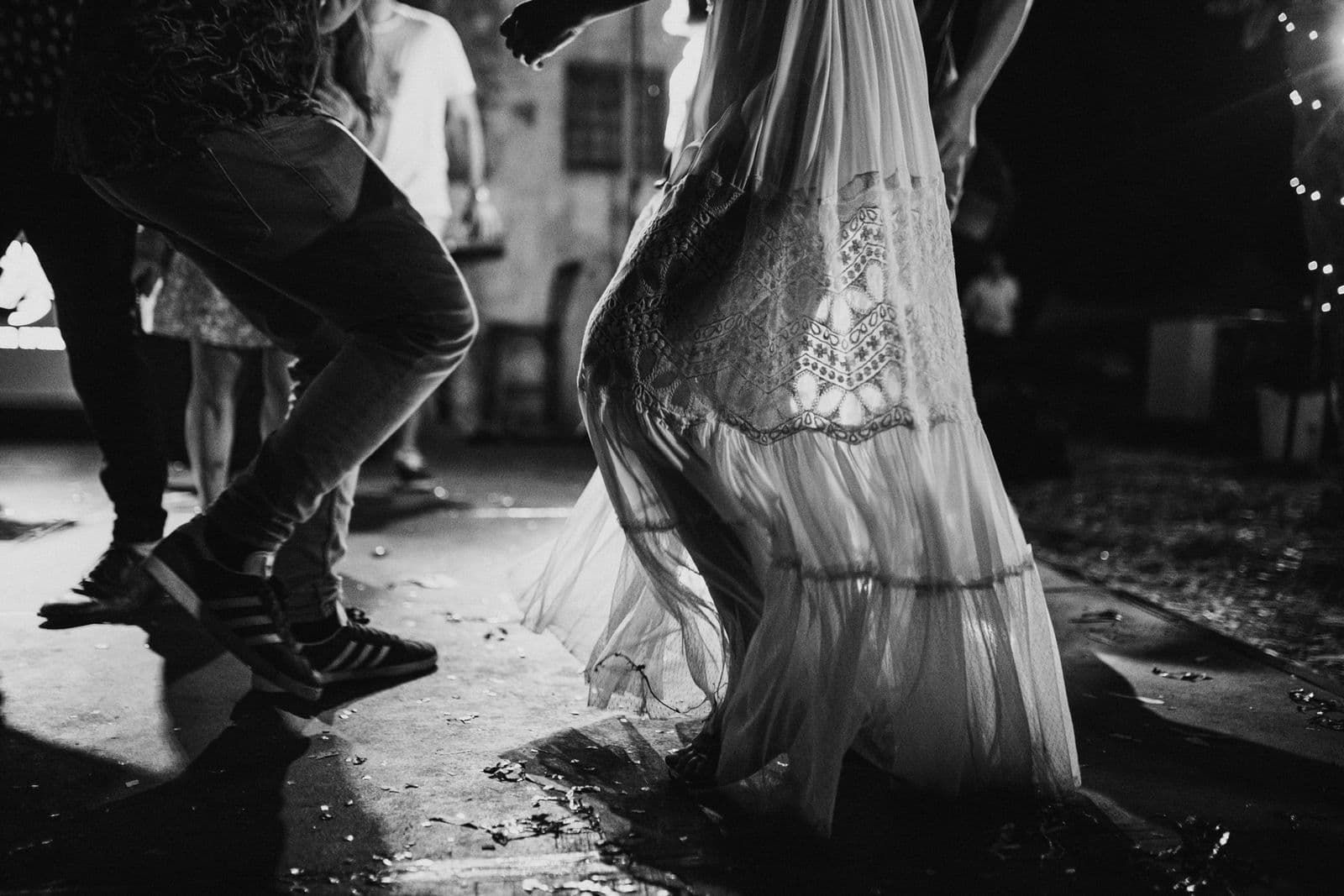 Feet in trainers and a lace dress mid-dance on a confetti-covered floor
