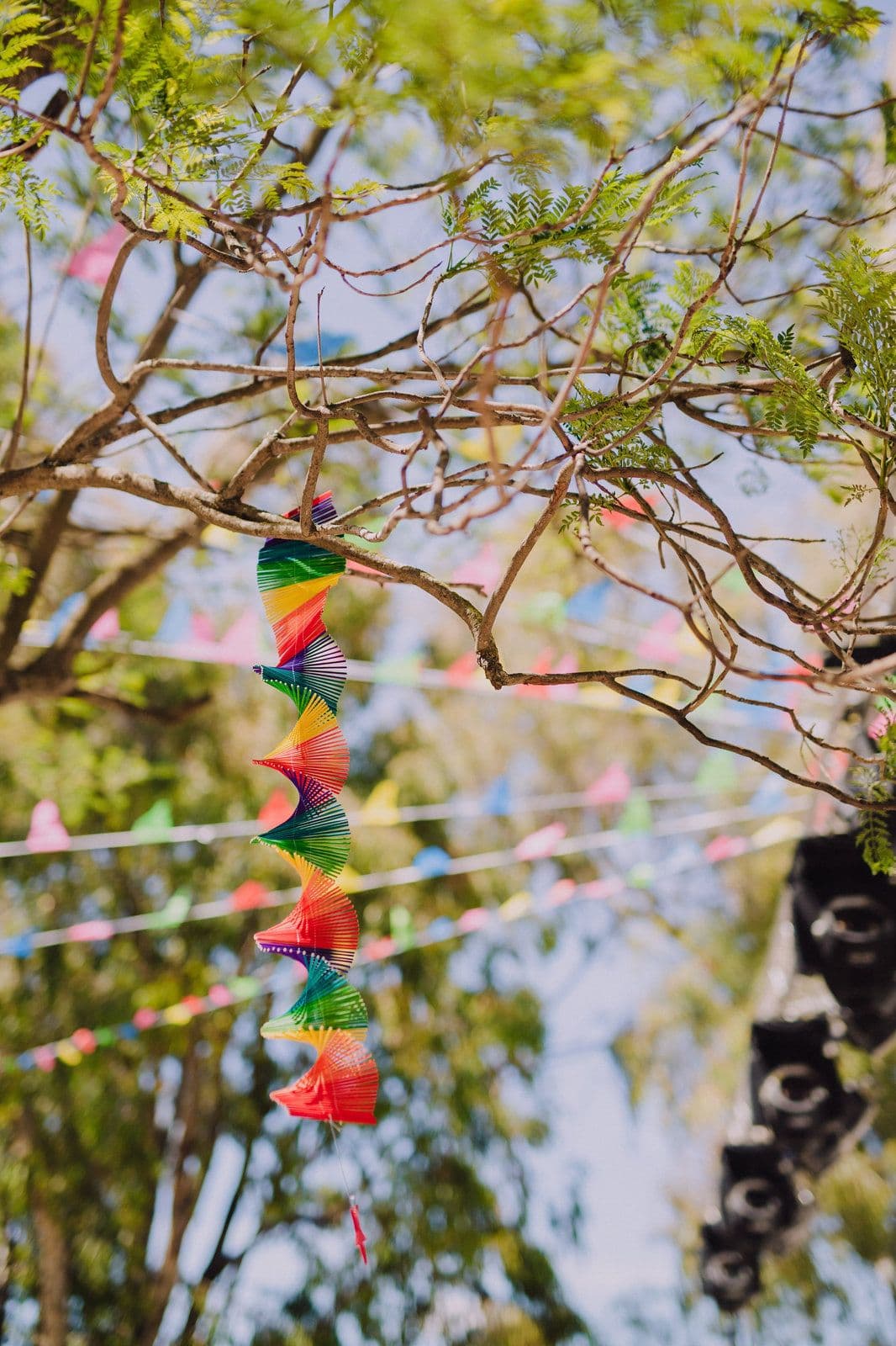 A rainbow paper spiral and bunting hanging from a tree