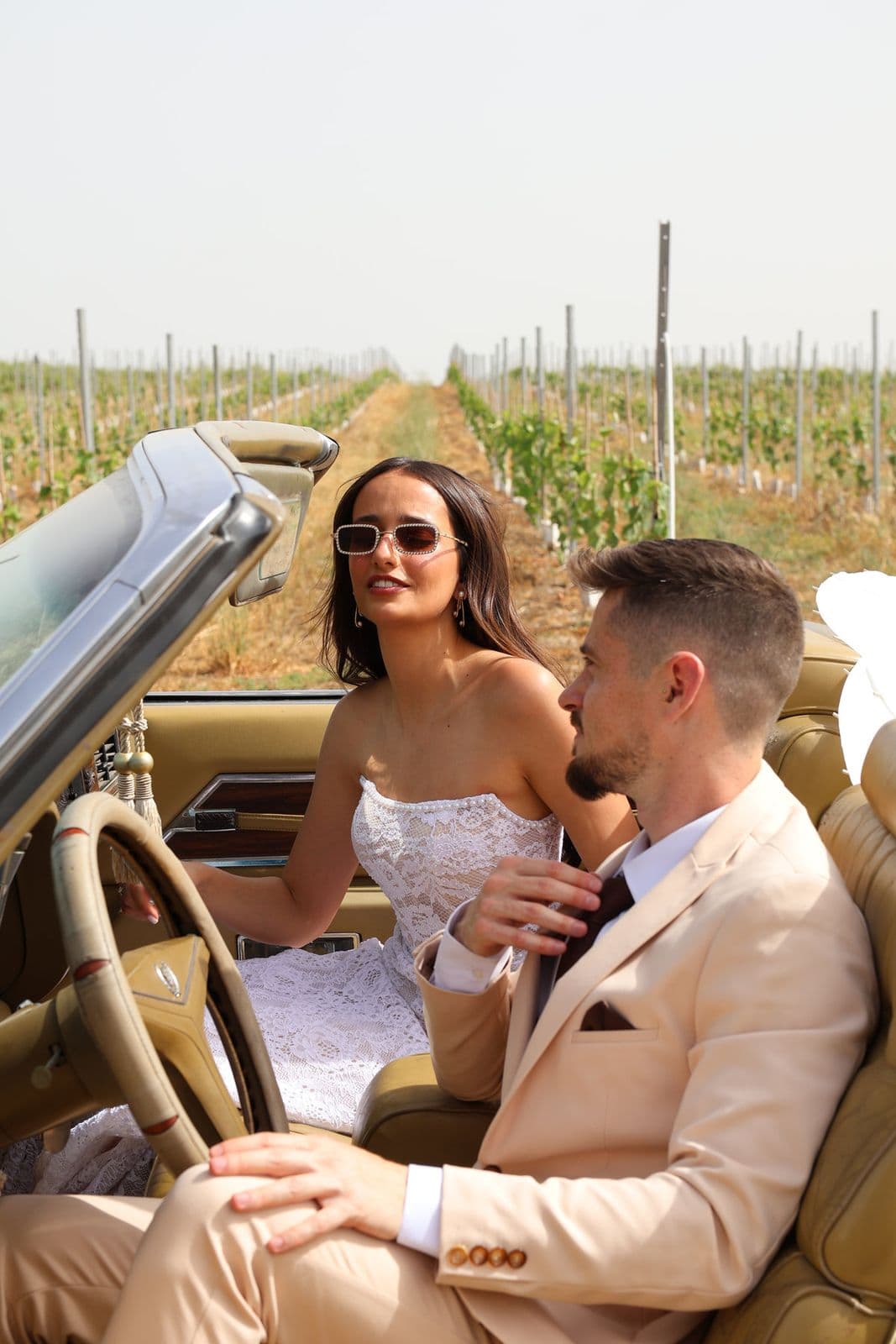 A newly married couple in a vintage convertible between the vines